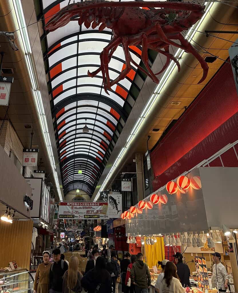 Tourists walking through Kuromon Ichiba Market in Osaka, exploring local street food and stalls