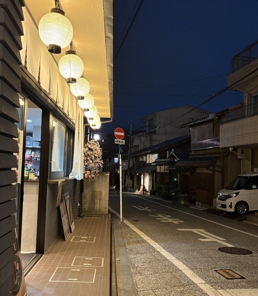 Atmospheric Kyoto side street at night with glowing lanterns and traditional restaurants near downtown.
