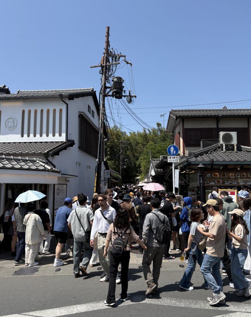 Tourists walking along the path toward a famous temple in Kyoto, surrounded by traditional scenery.
