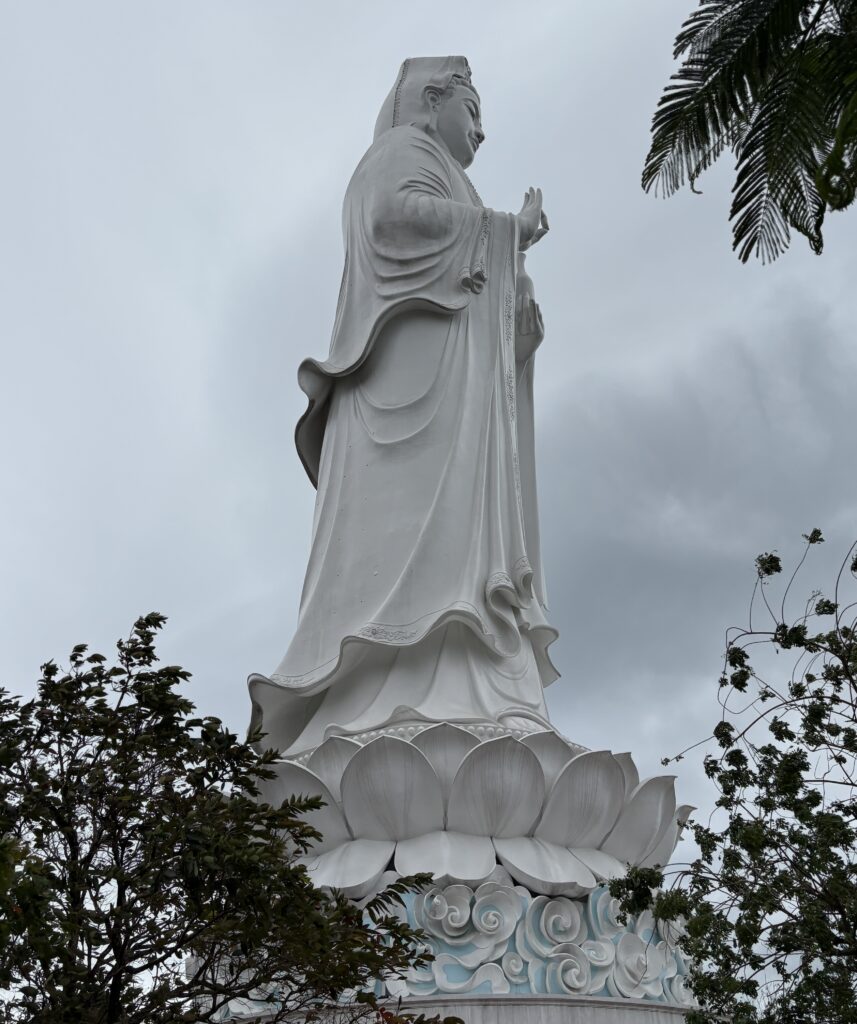 Close-up view of the towering Lady Buddha statue in Da Nang, Vietnam, showcasing its serene expression and intricate robe details against a clear sky.