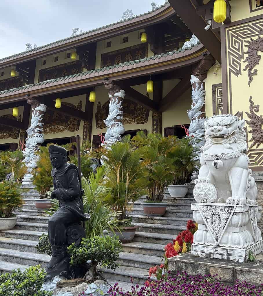 Multiple statues and a peaceful temple complex surrounding the iconic Lady Buddha in Da Nang, Vietnam, with lush greenery and spiritual ambiance.