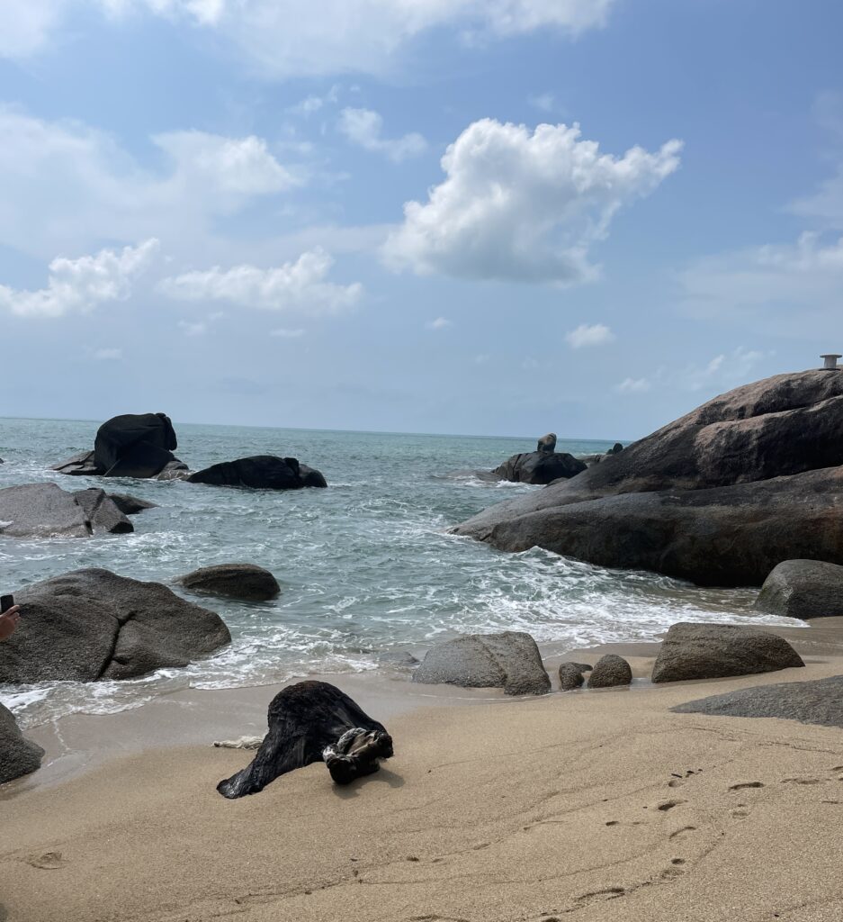 Scenic view of large rocks at the end of Lamai Beach in Koh Samui on a clear sunny day, with turquoise water and sandy shoreline
