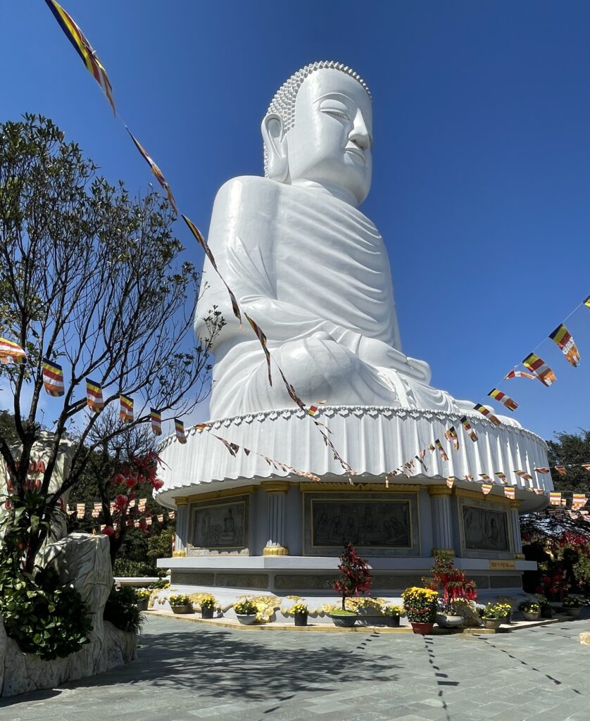 A towering Buddha statue standing tall at the Ba Na Hills in Da Nang, Vietnam, surrounded by lush greenery.