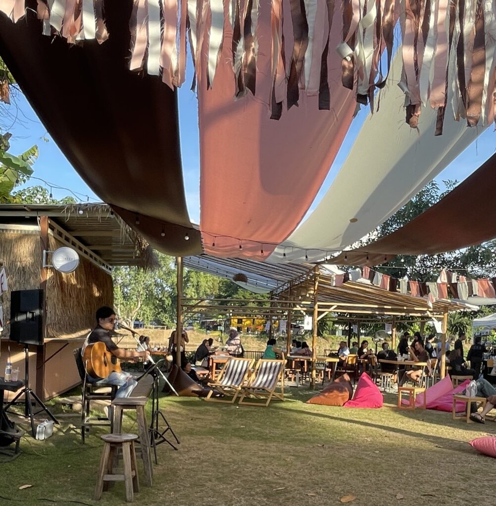 A man playing guitar at an outdoor café along the Ping River in Chiang Mai, Thailand.
