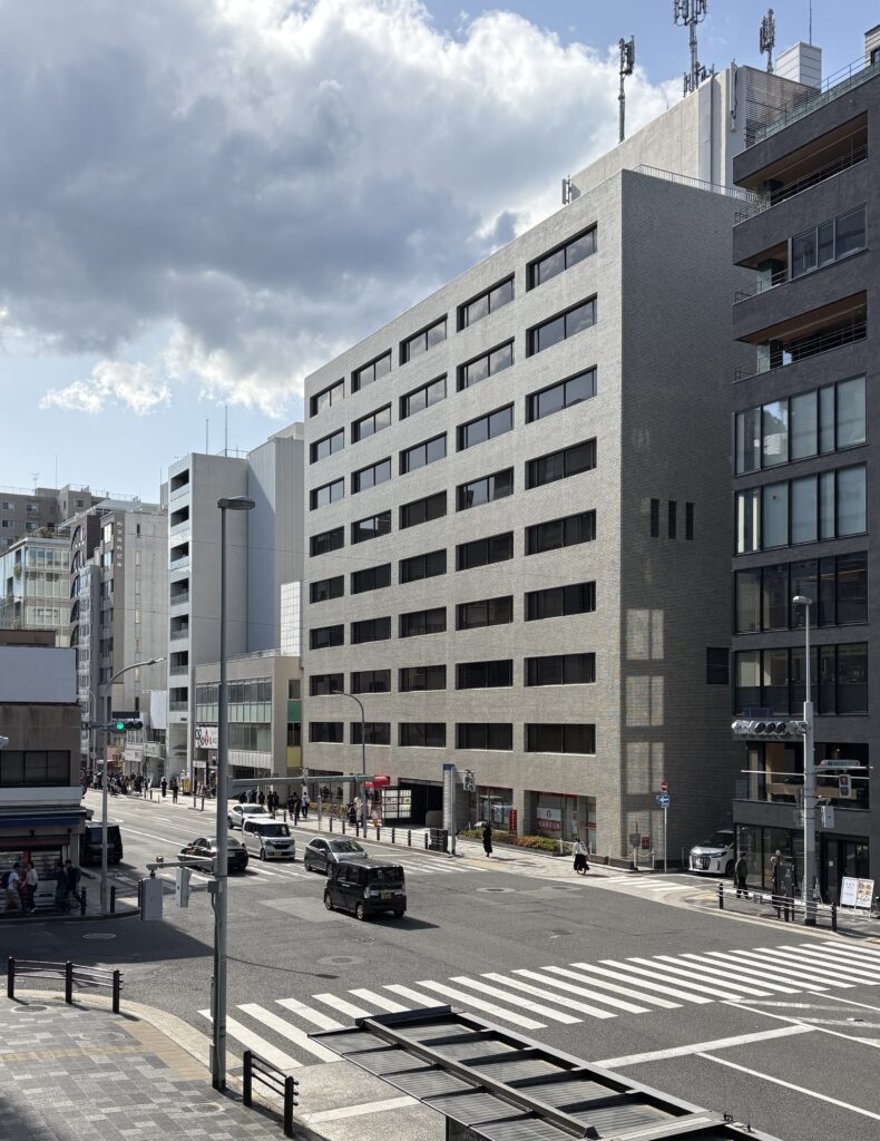 A modern street in Kyoto with cars passing by, lined with contemporary buildings and city infrastructure.