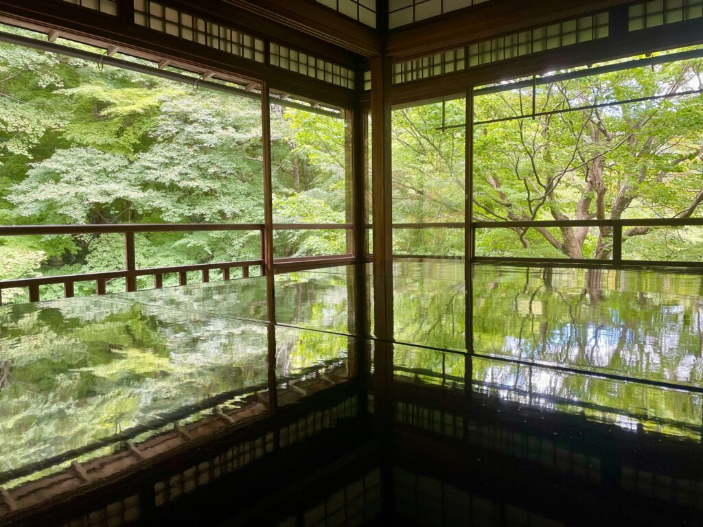 Traditional wooden interior of a ryokan in Ohara, Kyoto, with lush green nature visible through the open sliding doors.
