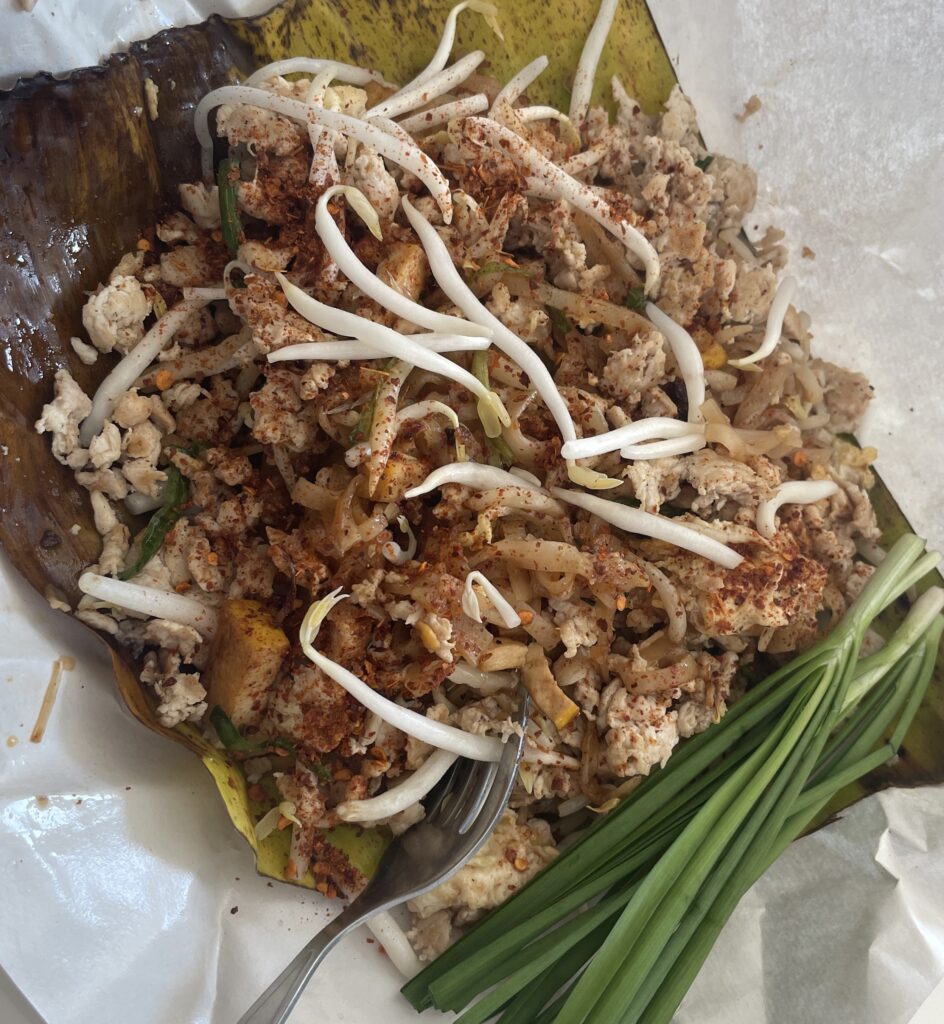 A plate of Pad See Ew served on a banana leaf with plenty of chilies during a Chiang Mai cooking class.
