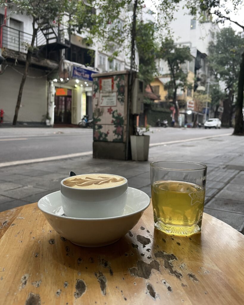 A cup of salt coffee served with Jada, a traditional Vietnamese iced tea, on a Hanoi street-side café table.