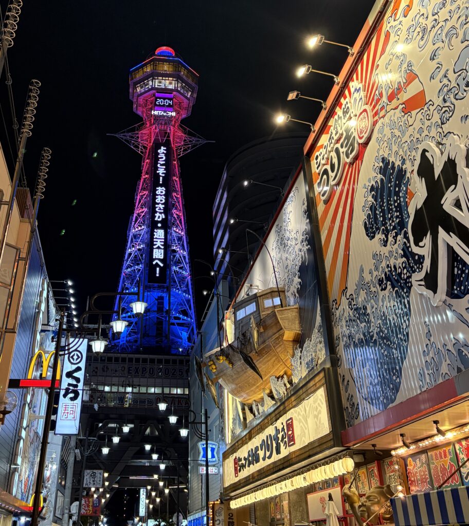 Tsutenkaku Tower surrounded by bright signs in Shinsekai district
