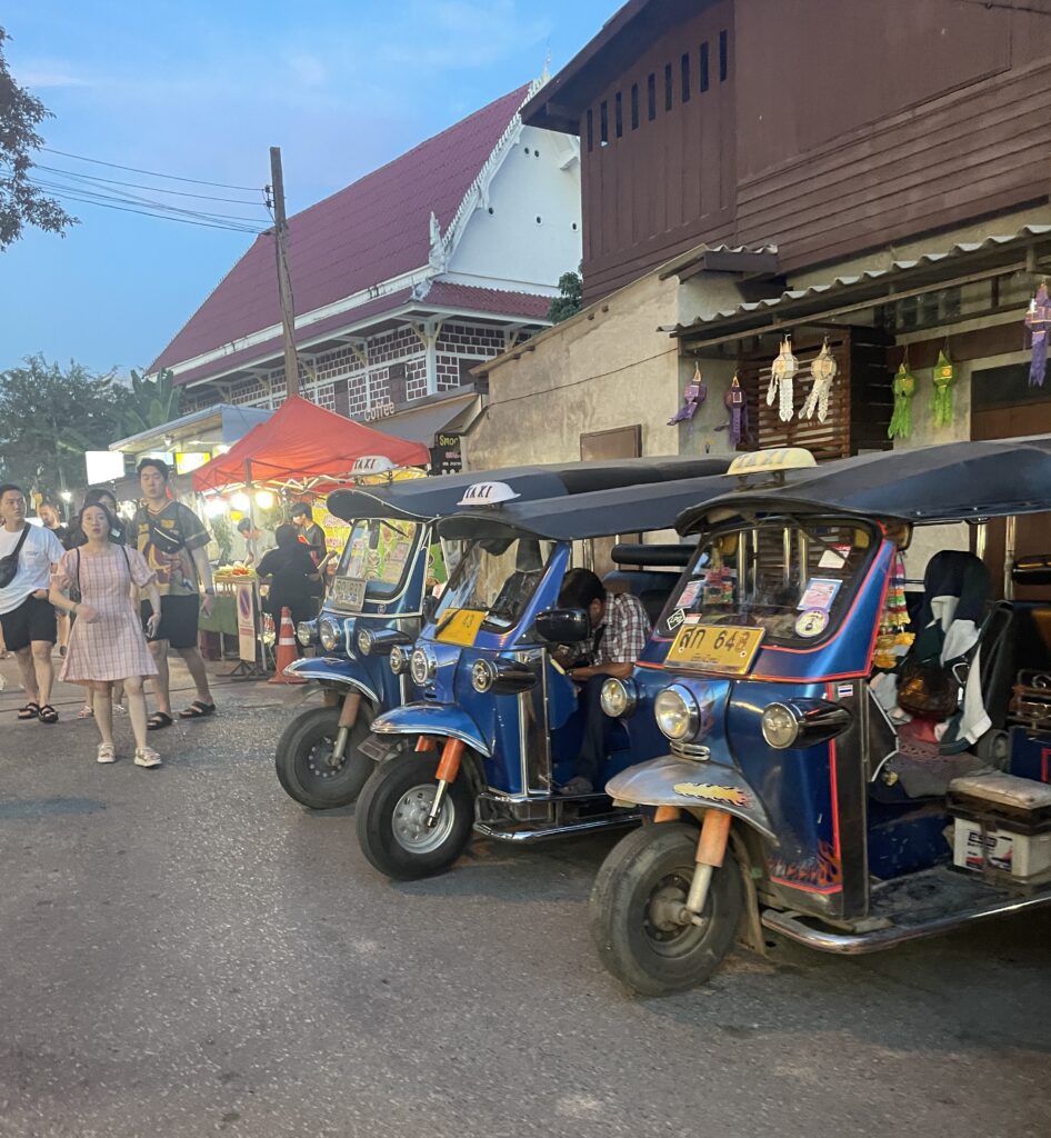 Three tuk-tuks parked at the Sunday Market in the Old City of Chiang Mai, Thailand.
