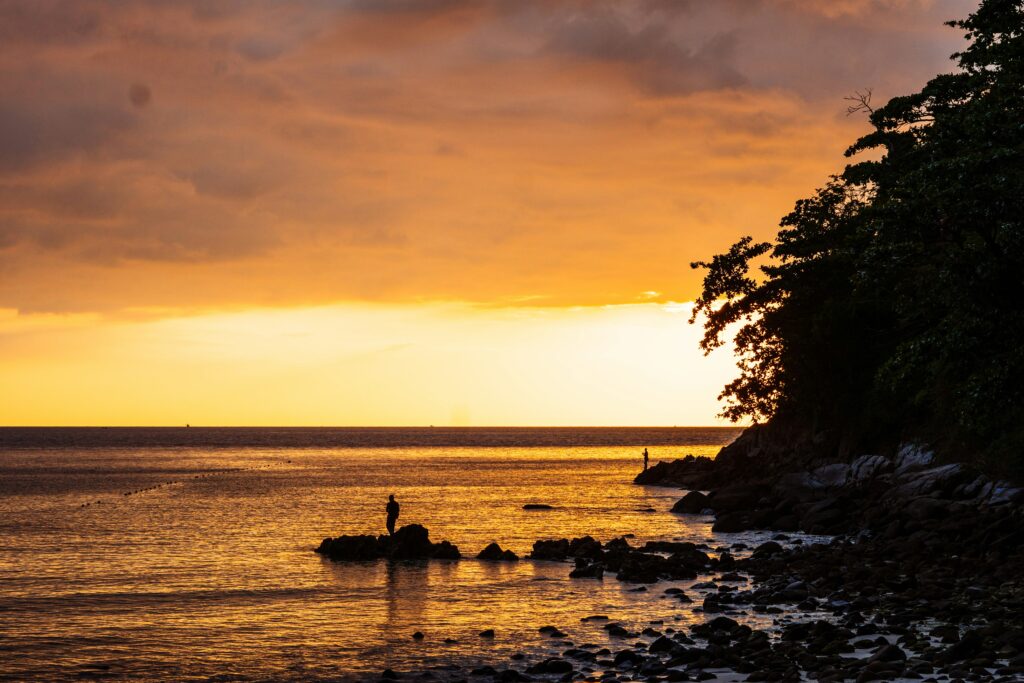 Vibrant Phuket sunset casting warm colors over the ocean and silhouetted coastline