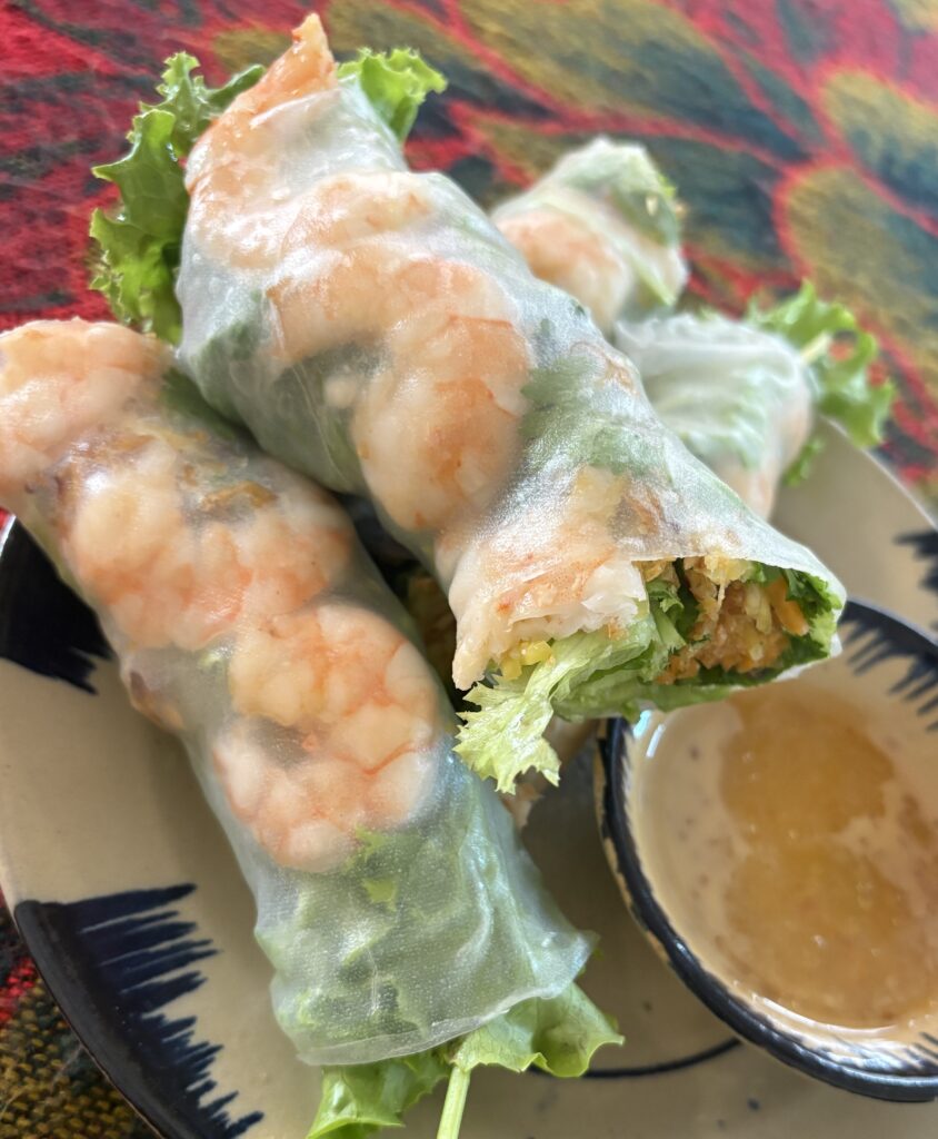 Close-up of fresh Vietnamese shrimp spring rolls with herbs and rice paper, served with dipping sauce, photographed in Da Nang.