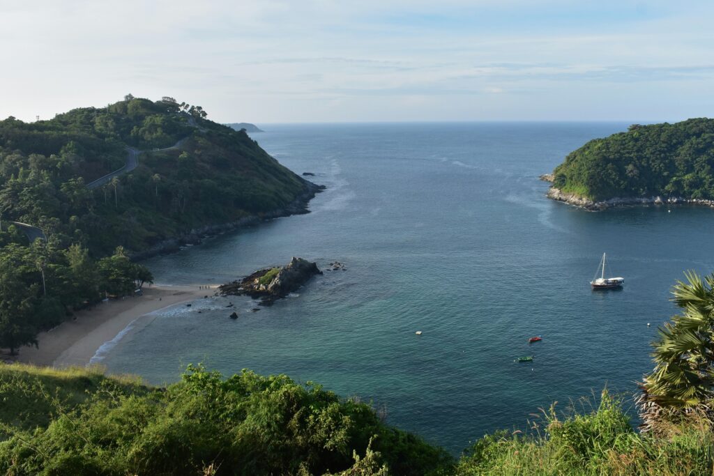 Aerial view of Ya Nui Beach in Phuket showing a curved shoreline, surrounding cliffs, and rocky outcrops from a high viewpoint.