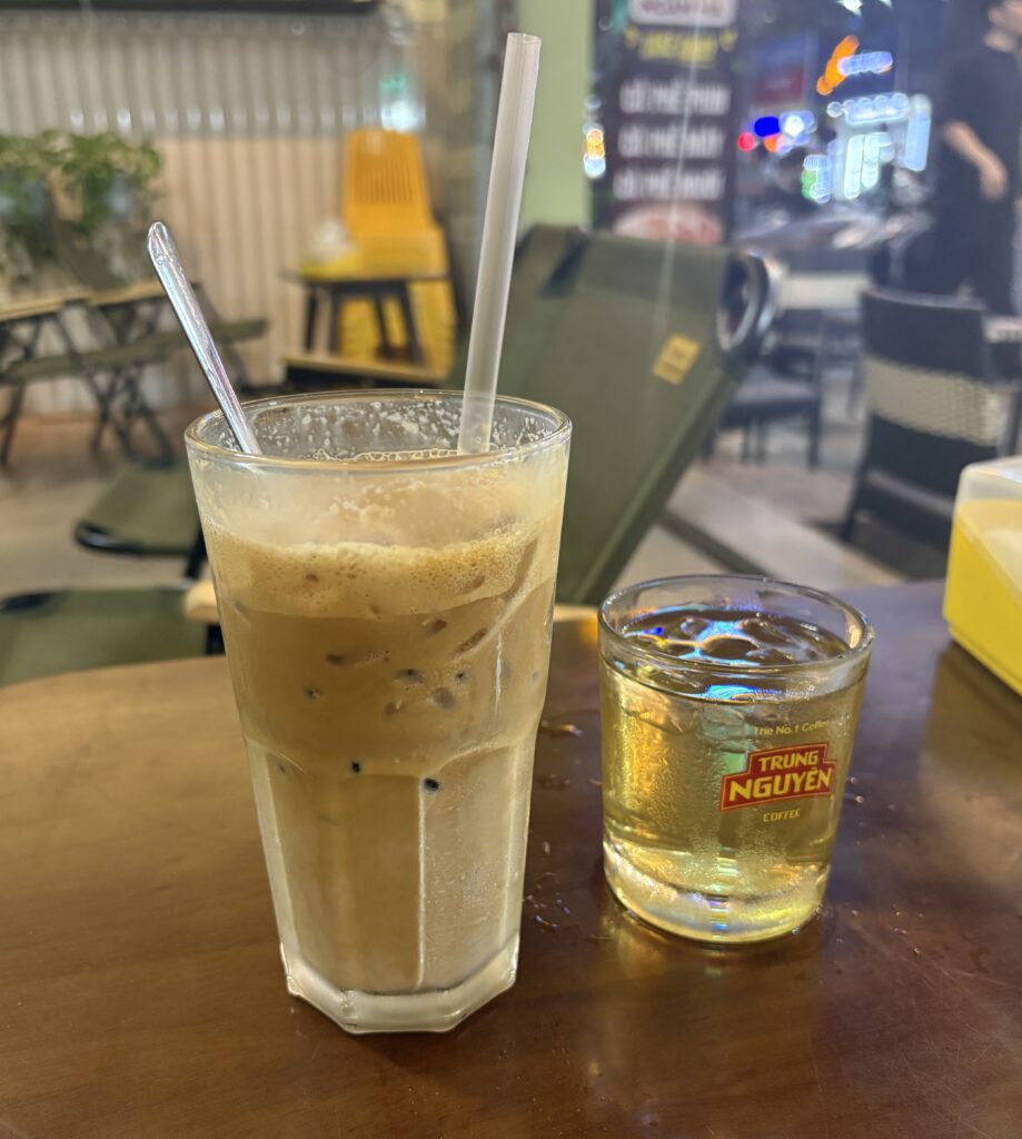 Cold avocado Vietnamese coffee served with a glass of tra da iced tea in Da Nang during the evening