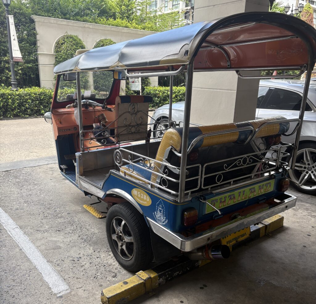 Close‑up of a classic Thai tuk‑tuk parked in Bangkok during the day, showcasing its colorful design and iconic style.