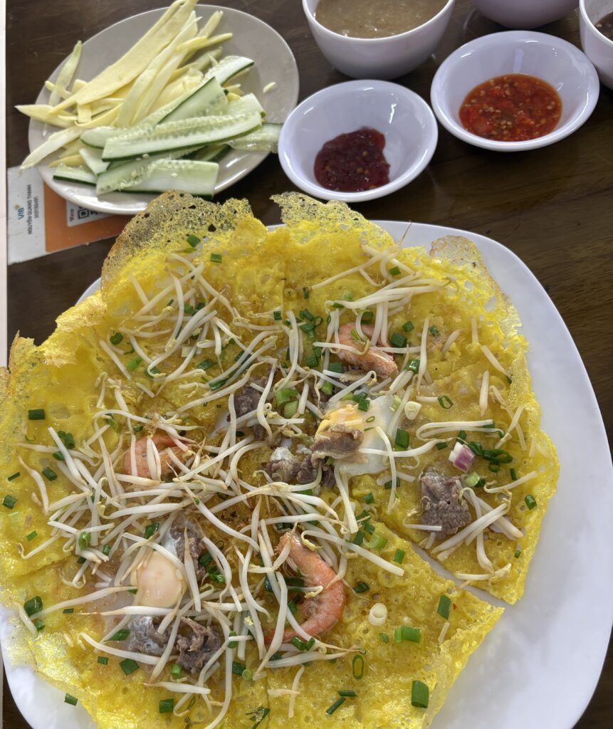 Banh xeo served in Da Nang with shrimp, beef, dipping sauces, and fresh toppings.