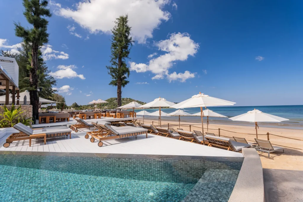 Clear sunny day at Catch Beach Club in Phuket with a pool, sunbeds, and the sea just steps away.