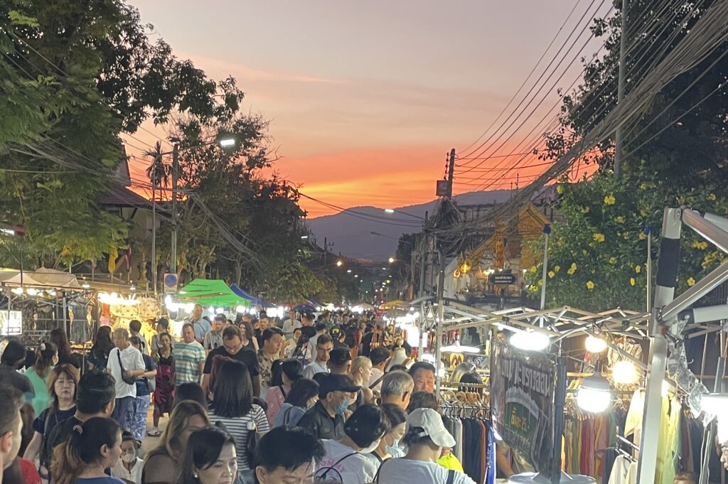 Chiang Mai Sunday Walking Street Night Market with tourists, locals, and a sunset over the mountains