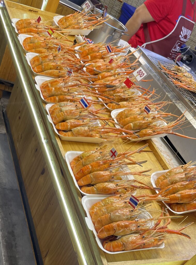 Massive prawns labeled with country flags at Jodd Fairs Night Market in Bangkok