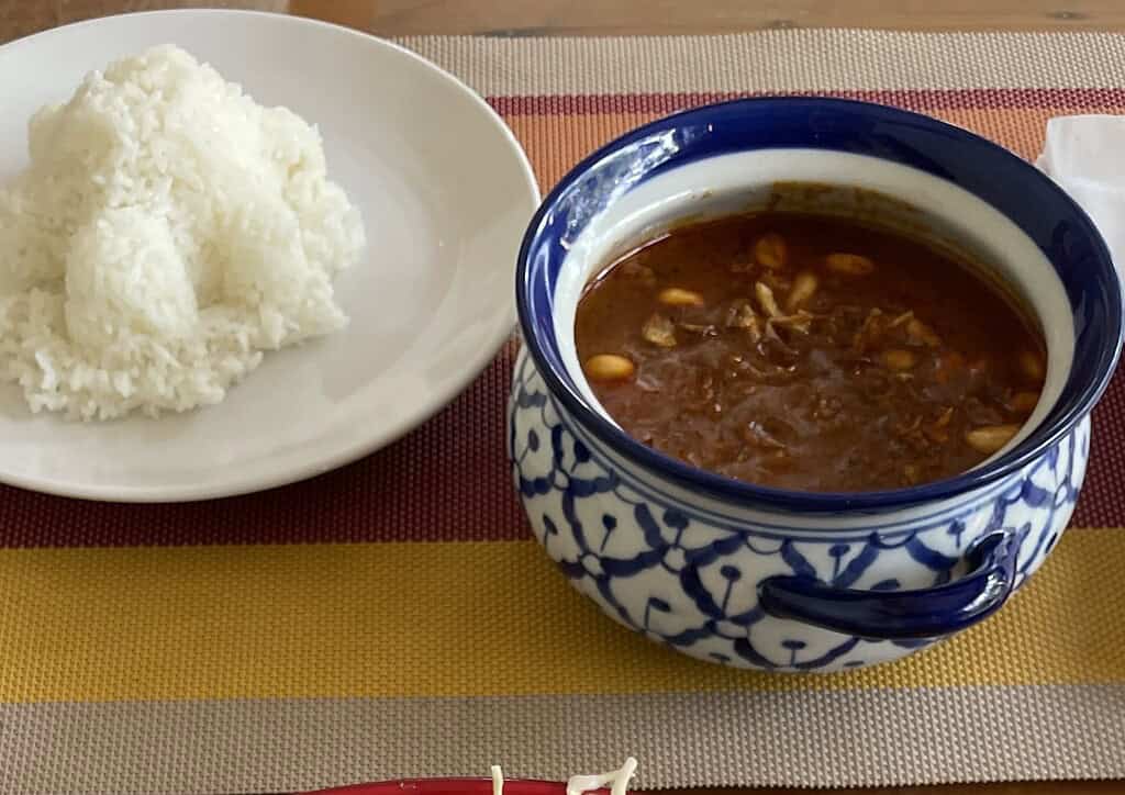 Bowl of rich Massaman curry served with a side of Thai rice in Krabi, Southern Thailand.