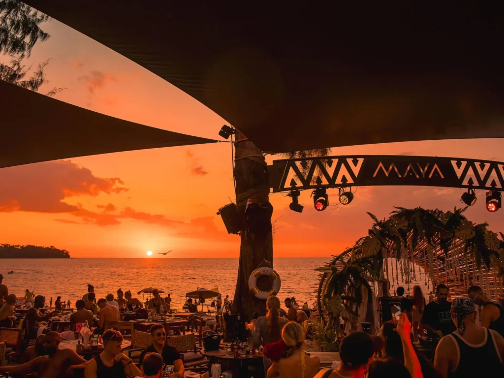 Maya Beach Club in Phuket at sunset with people dining and dancing on the beach.