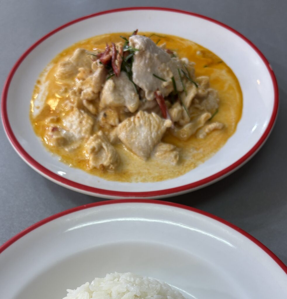 Panang Thai curry served with tender meat and creamy coconut sauce, with steamed rice on the side at a table in Bangkok.