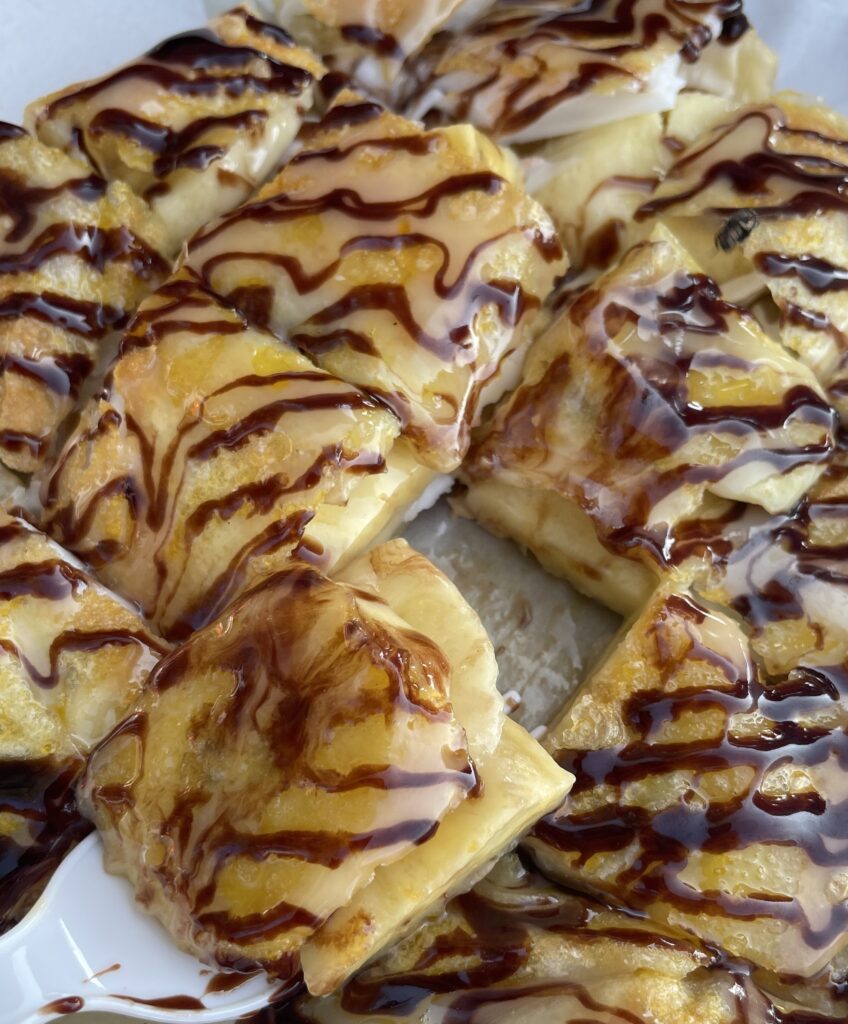 Close‑up of Thai roti with banana dessert, drizzled with chocolate and served hot at a street stall in Phuket.