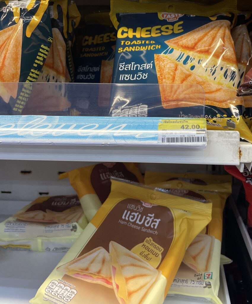 Close‑up of Thailand 7‑Eleven toasties, showing the original and ham‑and‑cheese flavors on display at a 7‑Eleven store.