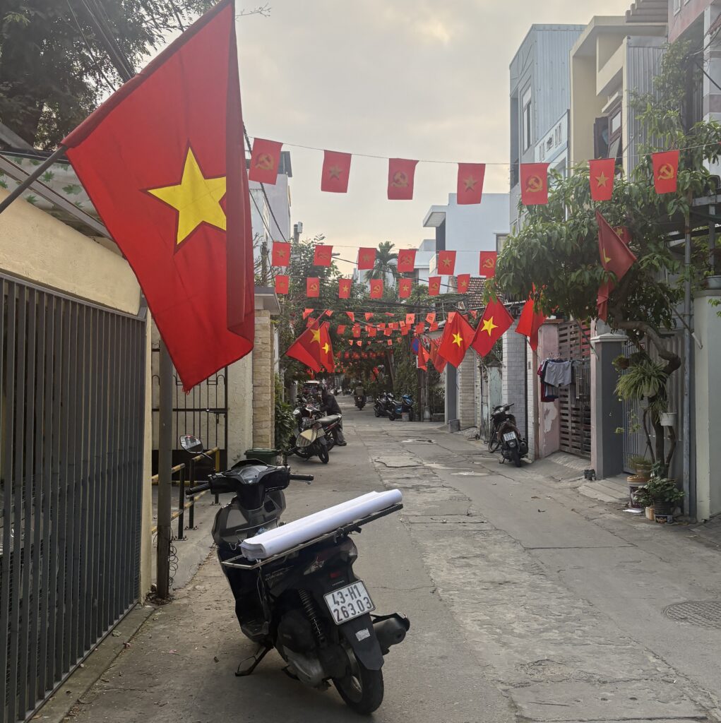 A vibrant Vietnamese alleyway filled with scooters and decorated with flags.