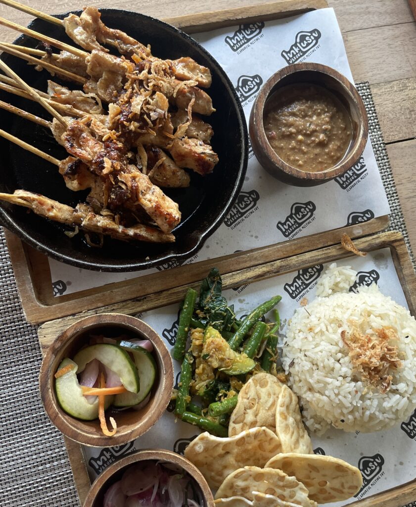 Local meal with chicken satay, peanut sauce, and rice at a warung in Canggu, Bali