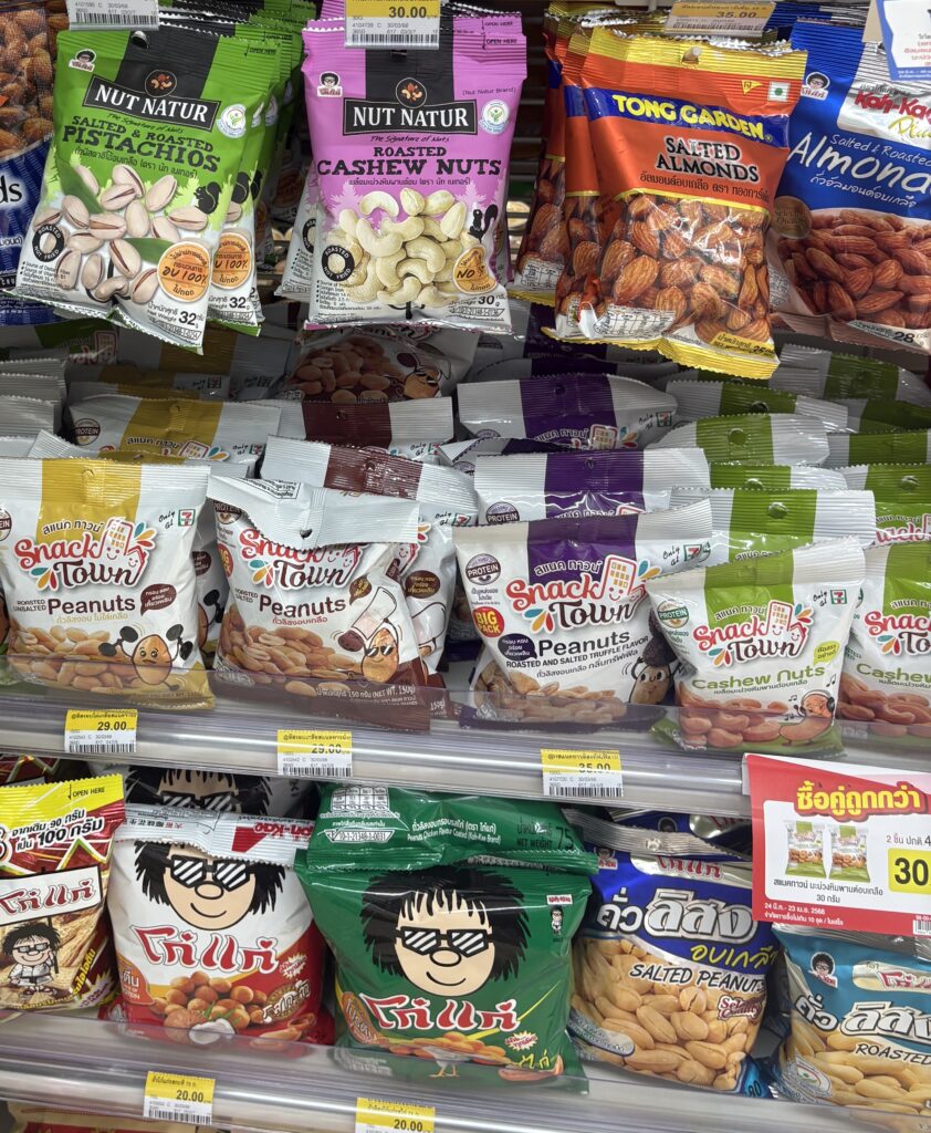 An array of peanut snacks in different flavors on display at a 7-Eleven store in Thailand, a popular spot for tourists to grab unique treats.