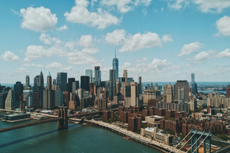 Aerial helicopter photo of New York City showing Manhattan, East River bridges, and skyline from a side angle.
