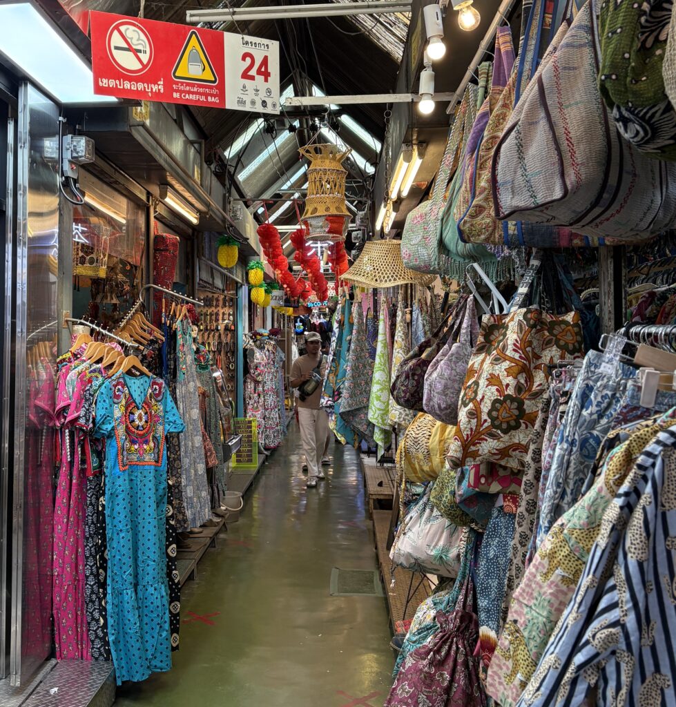 An aisle full of different clothing stalls at Bangkok’s Chatuchak Weekend Market, one of the best places to shop for souvenirs and local goods in Thailand.