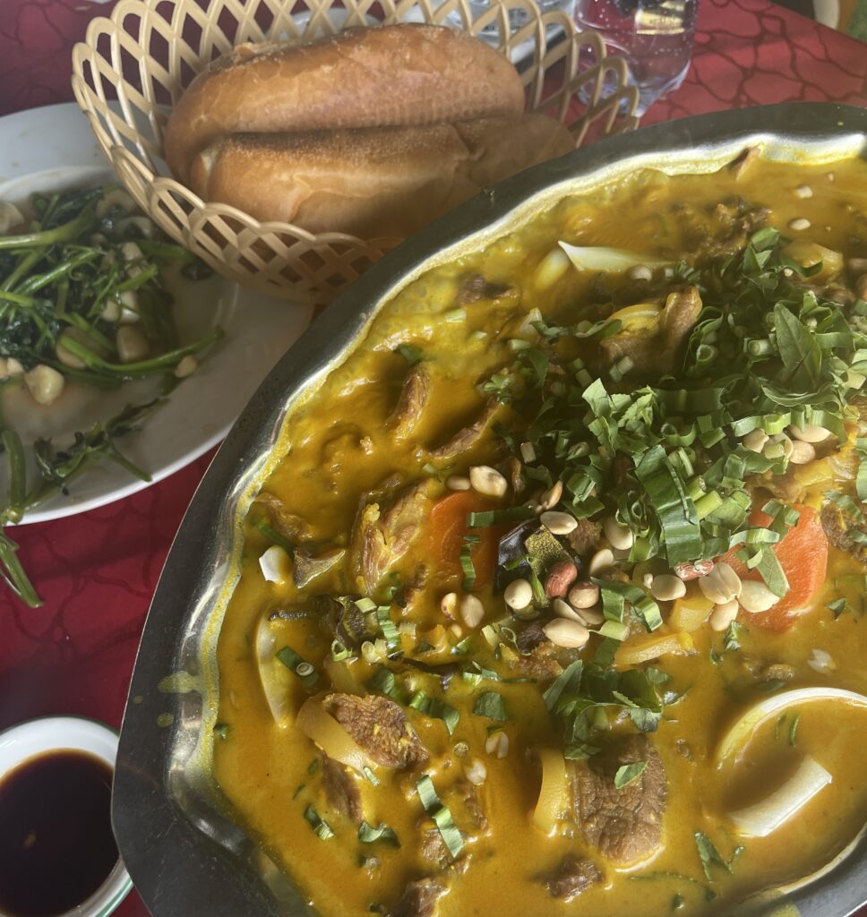 Goat curry served with fresh banh mi bread on a table in Saigon, Vietnam.
