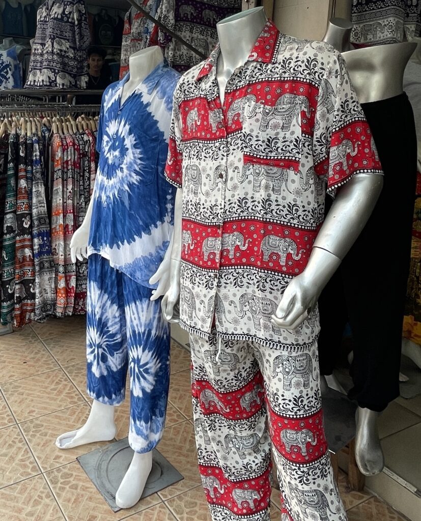 A mannequin dressed in colorful Thai elephant pants and a T-shirt on display at a market stall in Thailand.