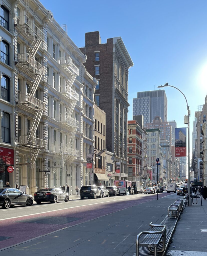 Wide New York City street with a designated bike lane, lined with buildings and city traffic.