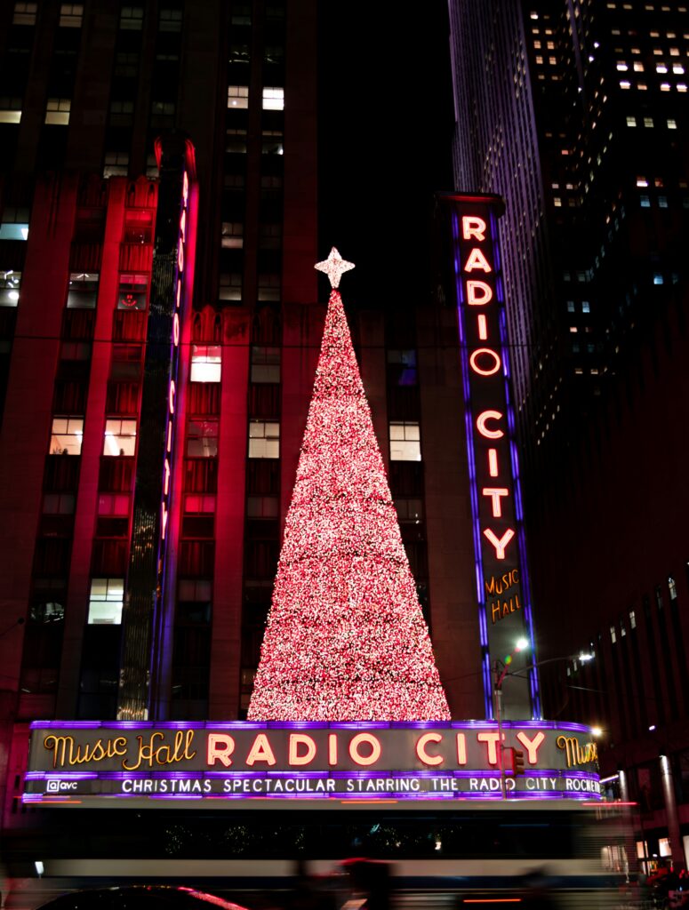 Lit-up Christmas tree by Radio City in New York City at night.
