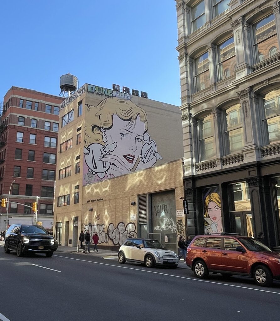 Street in Soho, New York City, featuring large colorful wall art and urban vibes.