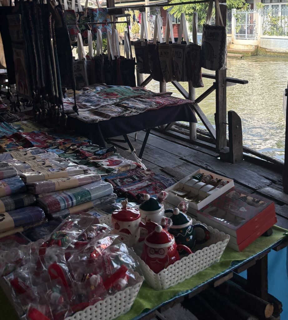 Small riverside shop in Bangkok’s water villages selling silk scarves, handbags, and local crafts.