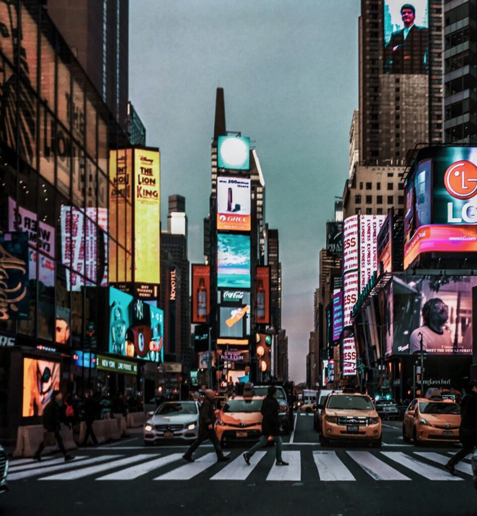 Street view of Times Square in New York City during the early evening with lights starting to glow