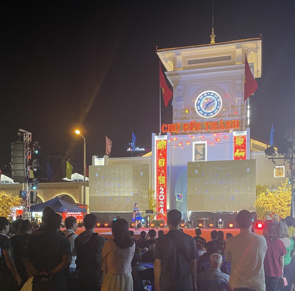 A festive crowd celebrating Tet in front of Ben Thanh Market in Ho Chi Minh City, Vietnam.