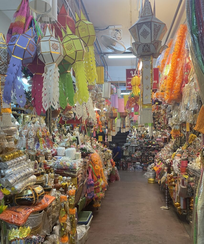 Wide array of snacks, fresh fruit, and colorful paper lanterns hanging above stalls at Warorot Chinatown Night Market in Chiang Mai.