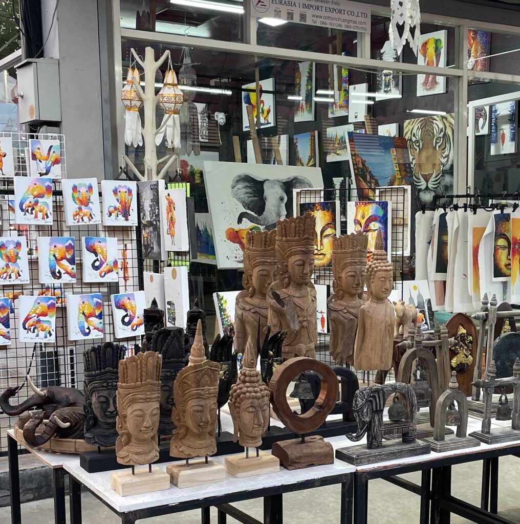 Rows of wooden Buddha statues for sale at a Thai market, a common spiritual souvenir in Thailand.
