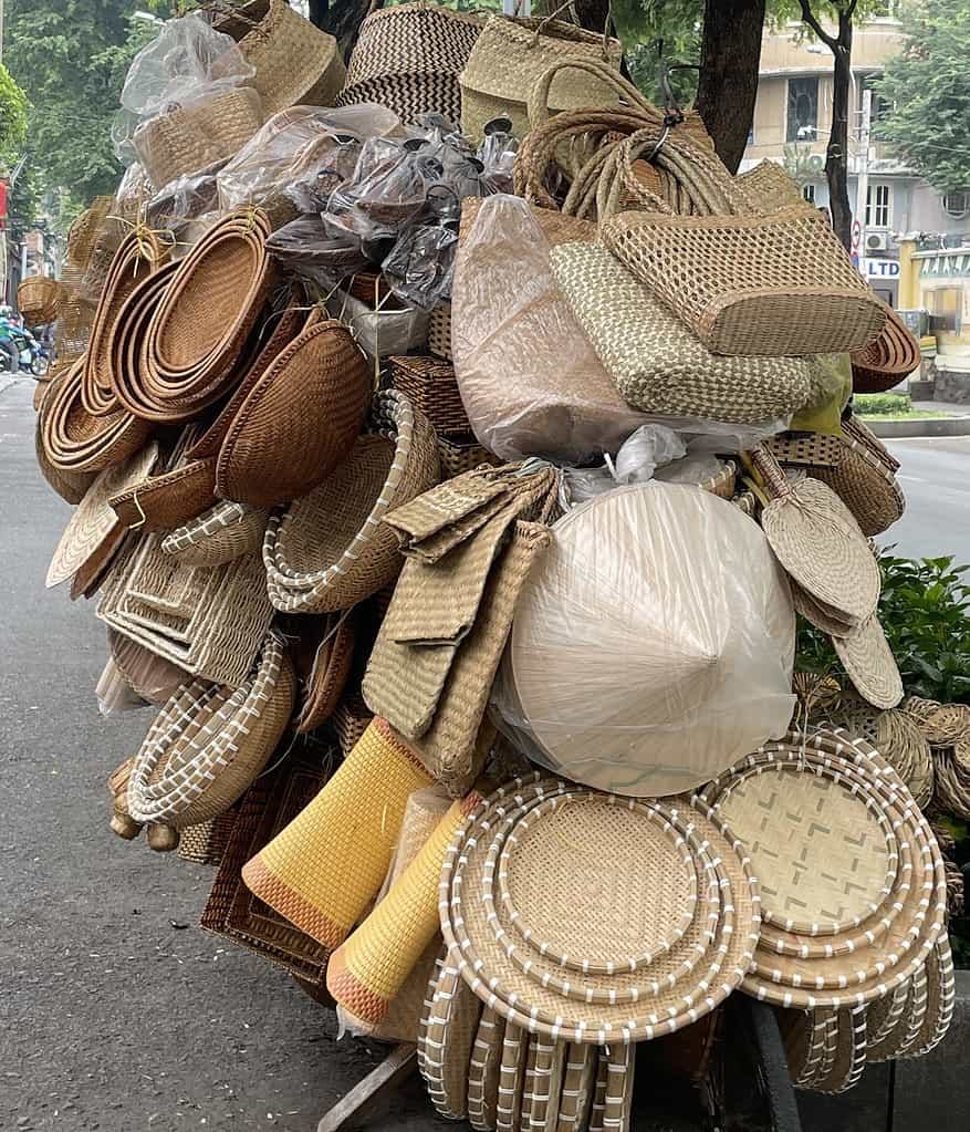 A bicycle in Saigon, Vietnam piled high with bamboo and rattan goods, including hats, baskets, and purses, showcasing traditional Vietnamese craftsmanship.
