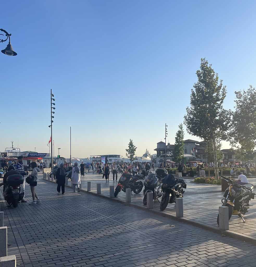 Locals and tourists walking along a cobblestone street by the waterfront in the lively Besiktas area of Istanbul.