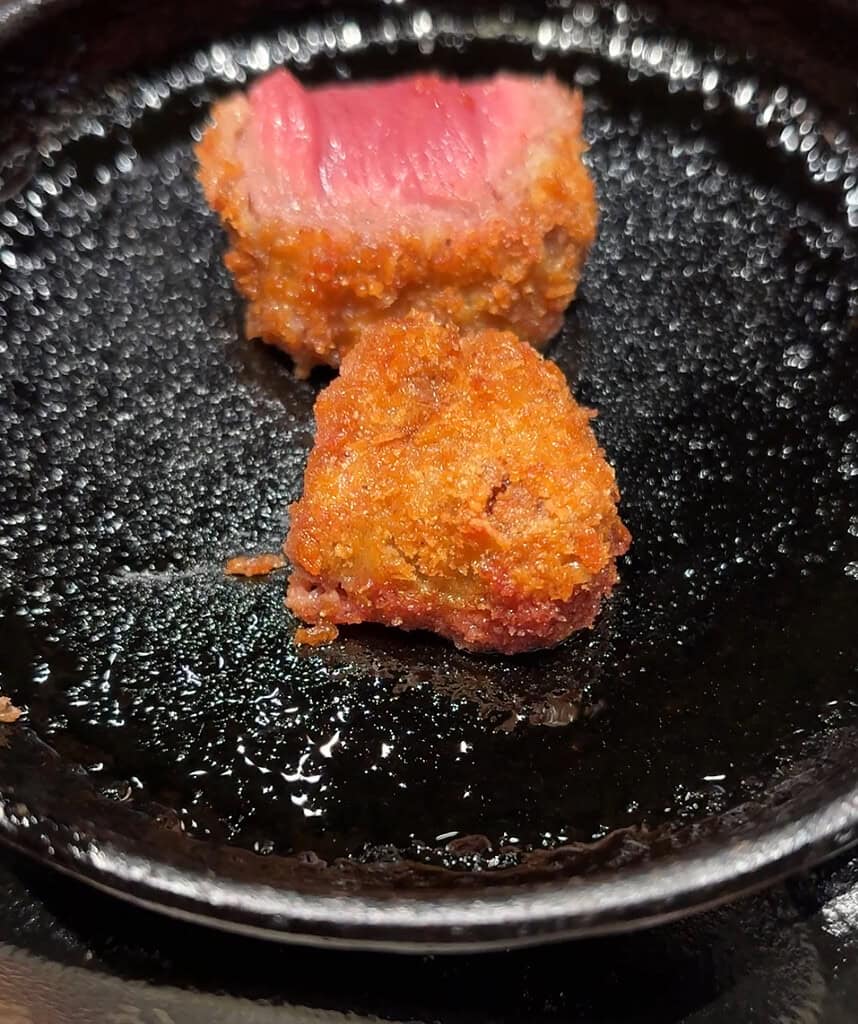 Steamy close-up of pink Gyukatsu cutlet at Motomura, slightly blurred from the rising heat.