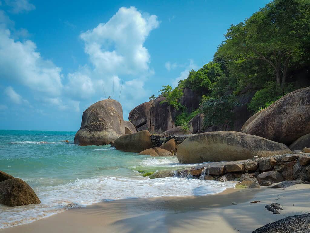 Stunning large rocks at the end of a beach in Koh Samui on a beautiful sunny day with clear sea water.