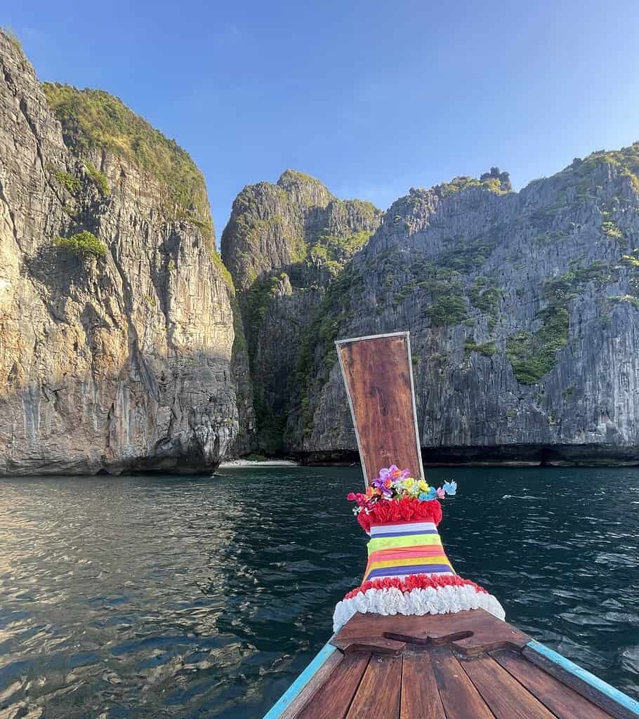 Close-up of a traditional Thai longtail boat in Phi Phi Island, with sunlight illuminating the limestone cliffs in the background.

