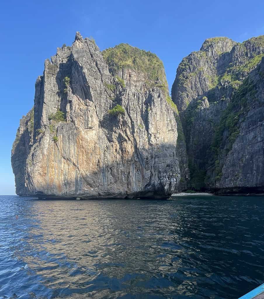 Stunning massive limestone cliffs rising from the waters of Phi Phi Island, illuminated by the early morning sun.