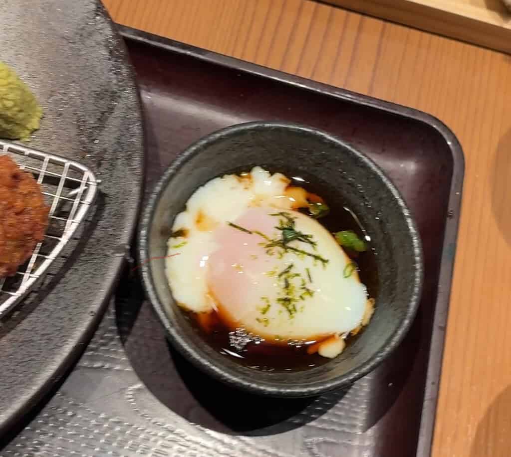 Soft poached egg served as a topping for gyukatsu, ready to be burst and mixed with the beef.
